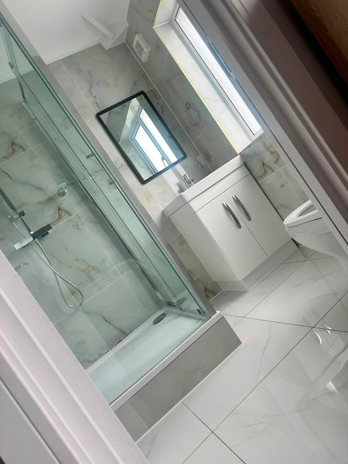 Completed bathroom with shower enclosure, vanity unit and marble-effect tiling