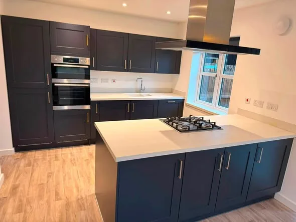 Completed dark fitted kitchen with island and light worktops by Hardy and Sons