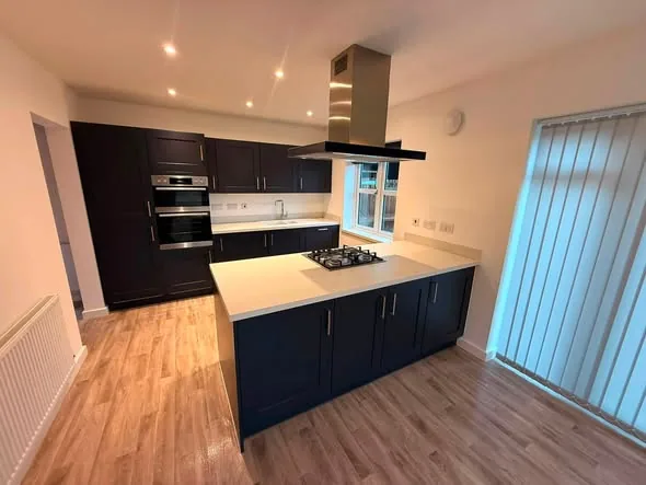 Finished kitchen installation with dark units and integrated oven housing